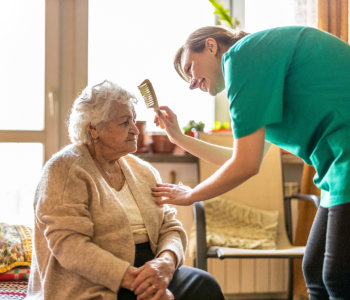 caregiver combs the hair of an elderly woman