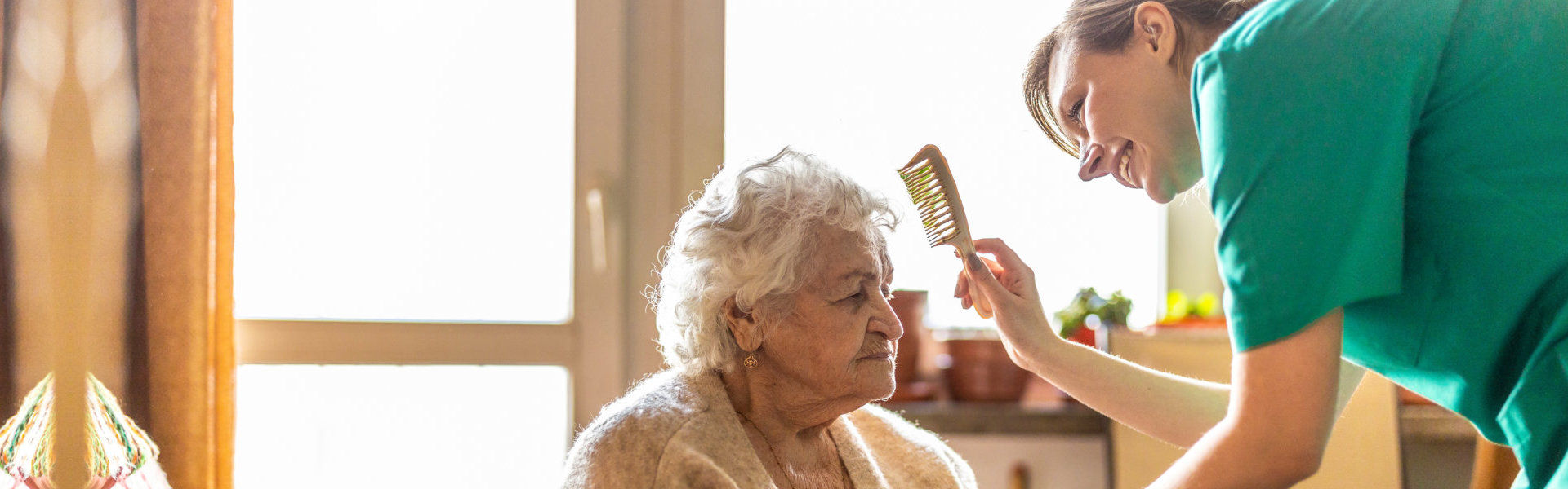 caregiver combs the hair of an elderly woman